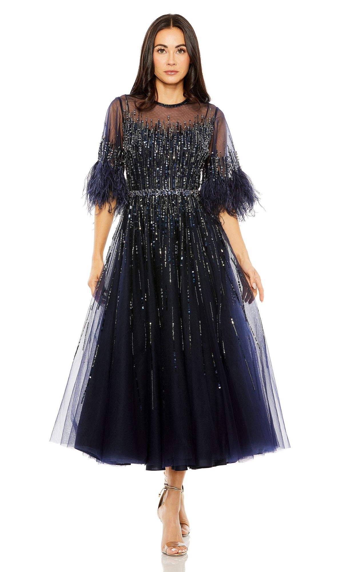 A woman in the Mac Duggal Navy Midi Wedding-Guest Dress 42097, featuring tulle fabric, feathered sleeves, and silver sequin embellishments, stands against a white background.